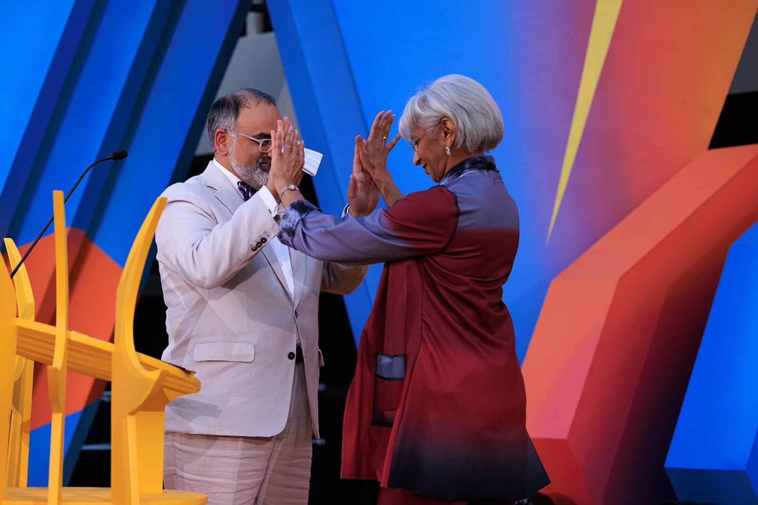 The president and new trustee share a double high five on the colorful graduation stage.