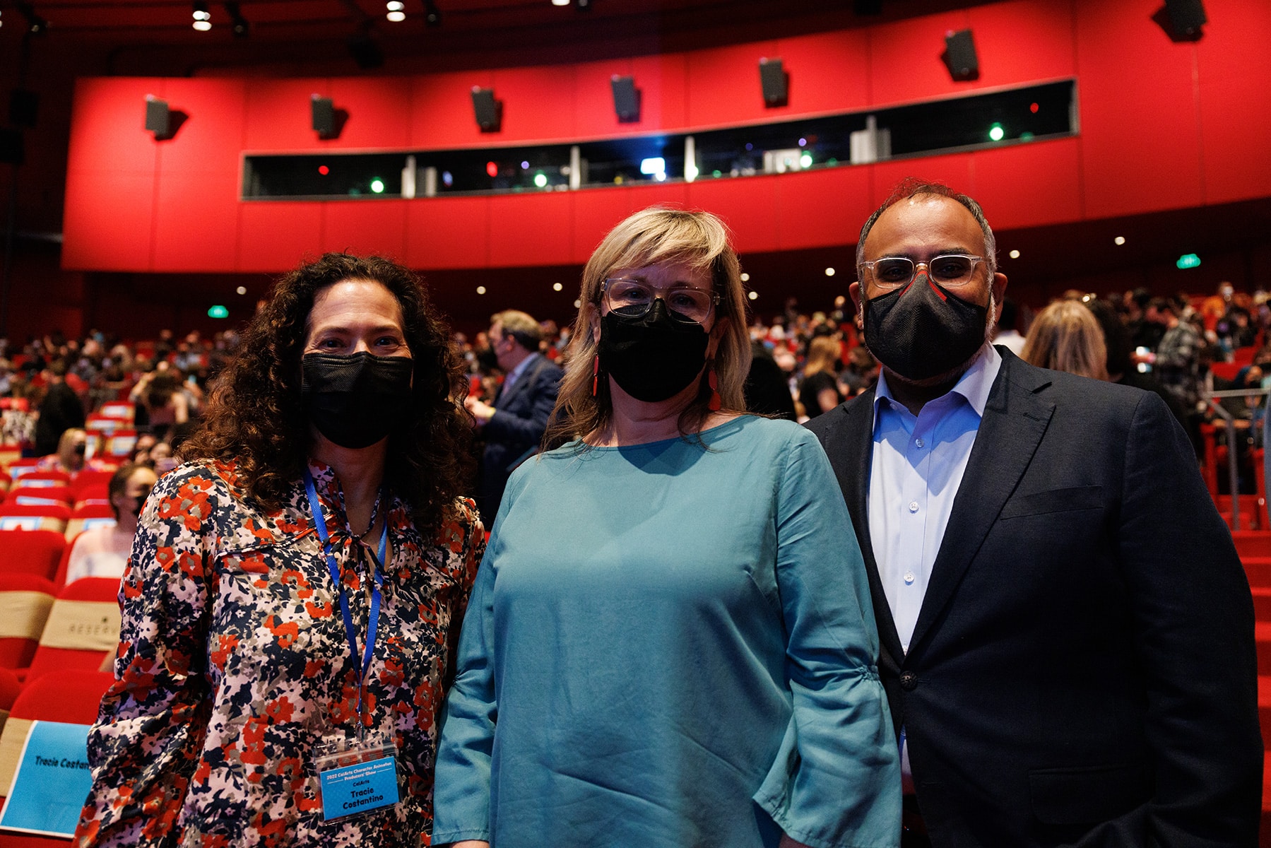 The three, wearing masks, stand side by side in the theater.