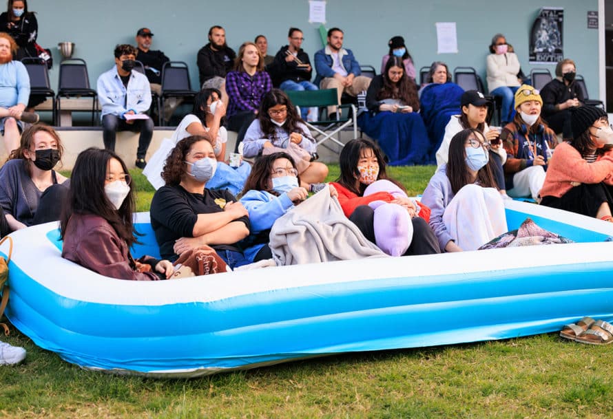 Group of students sitting in an inflatable pool on the lawn.