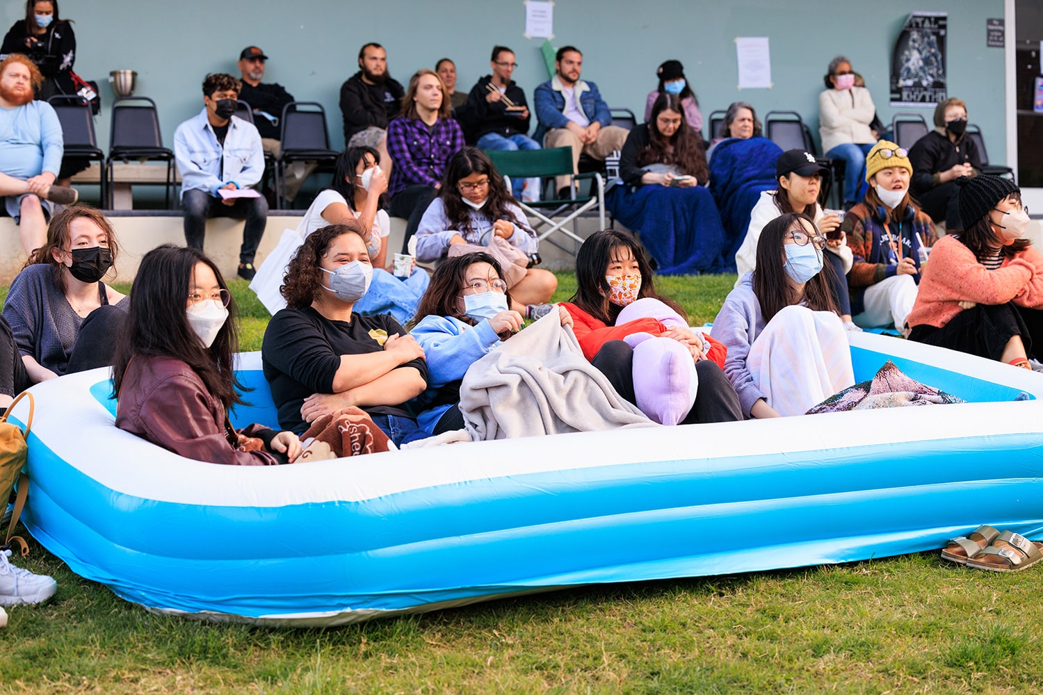 Group of students sitting in an inflatable pool on the lawn.