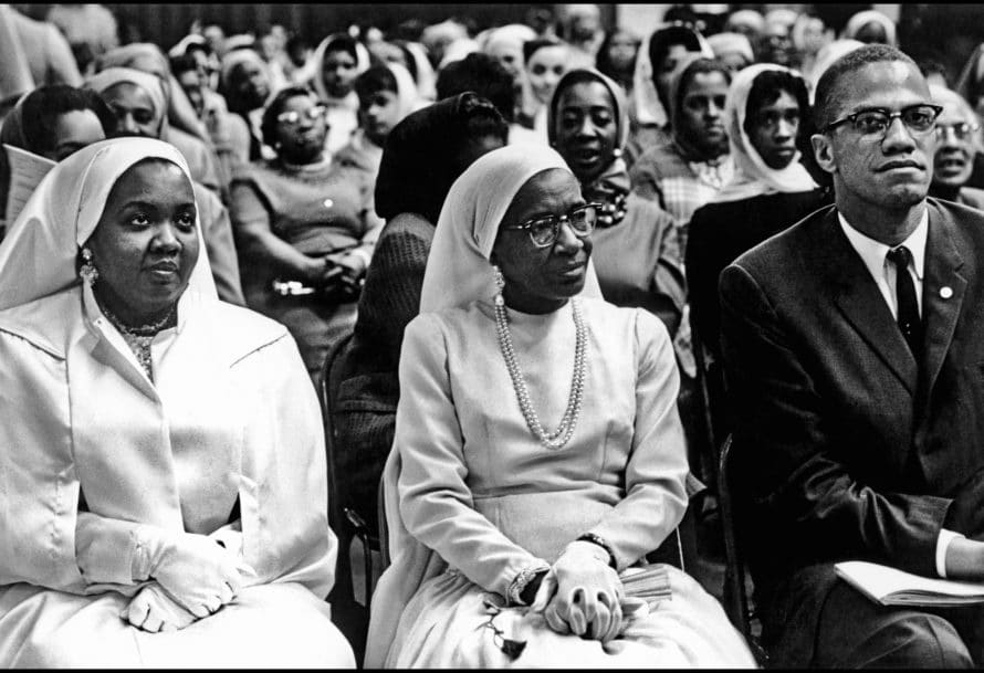 Black Muslims Meeting. USA. Chicago, Illinois. 1962. Daughter and wife of Elijah Mohammed with Malcolm X. | Photo: Eve Arnold/Magnum Photos.