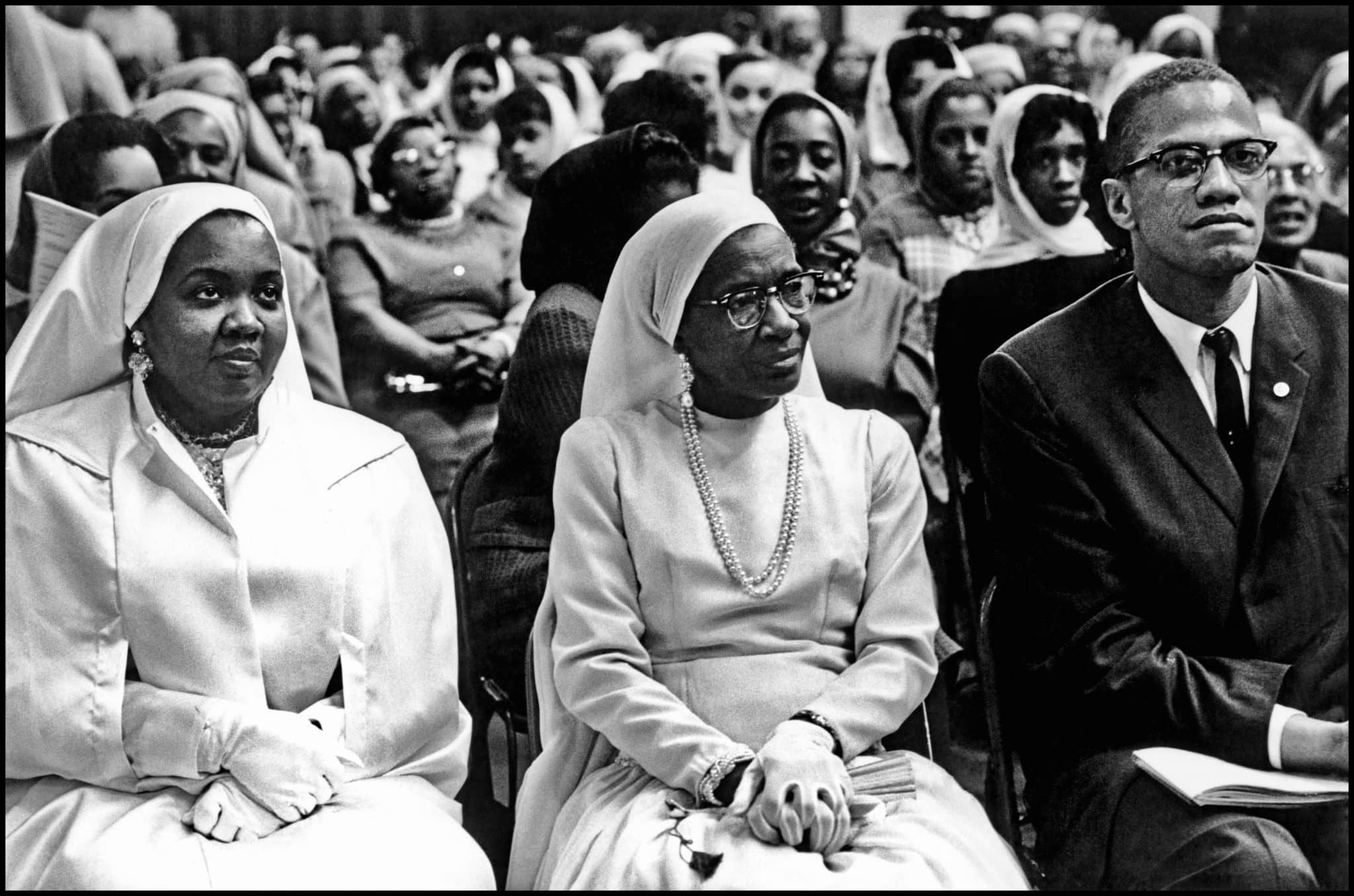 Black Muslims Meeting. USA. Chicago, Illinois. 1962. Daughter and wife of Elijah Mohammed with Malcolm X. | Photo: Eve Arnold/Magnum Photos.