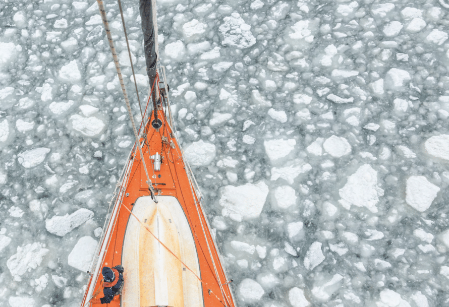 Tip of orange sailboat in icy water