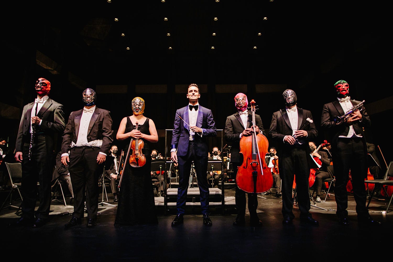 Six soloists wearing luchador masks stand either side of Juan Pablo Contreras on stage