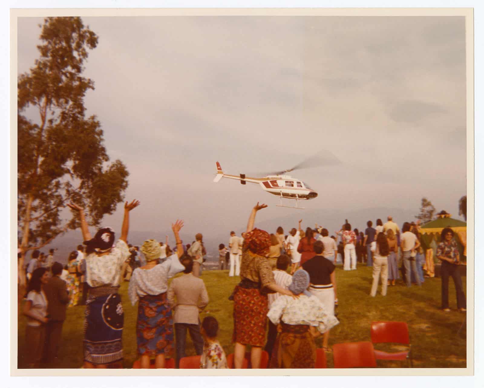Group of people on lawn waving at helicopter