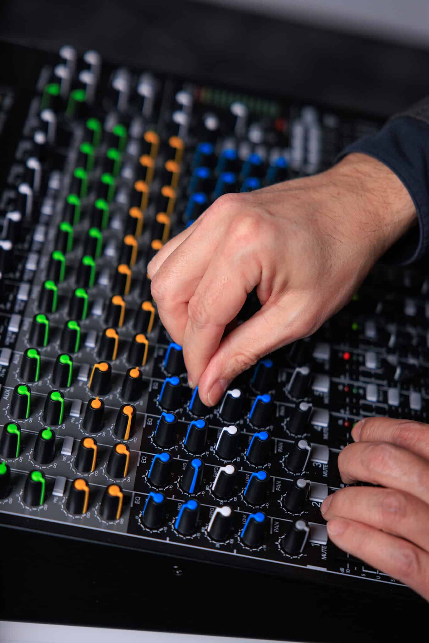 Hands twisting dial on mixing console