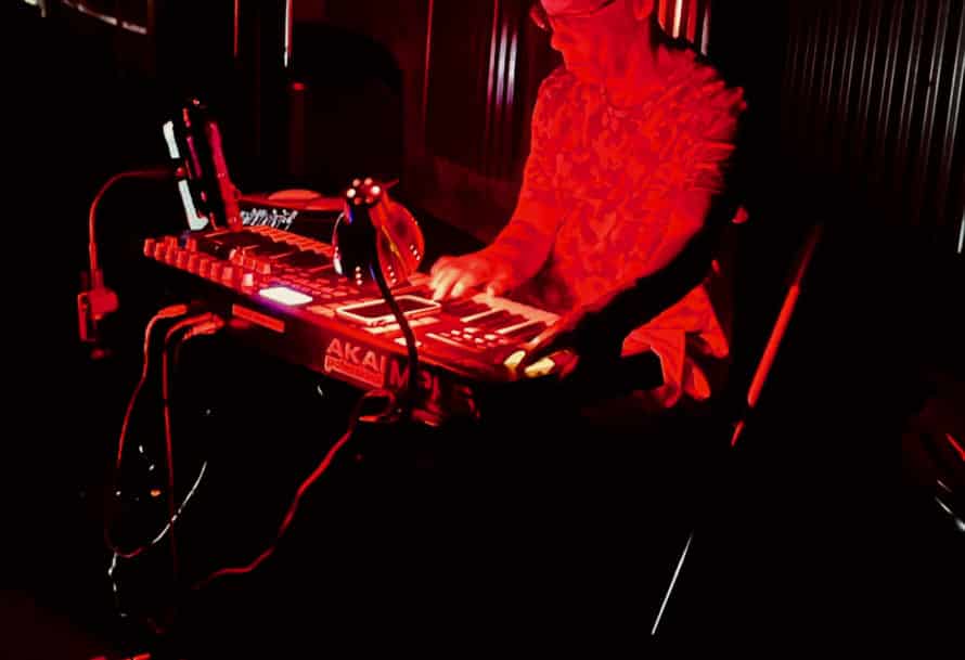 David Scott playing electronic music, bathed in bright red light