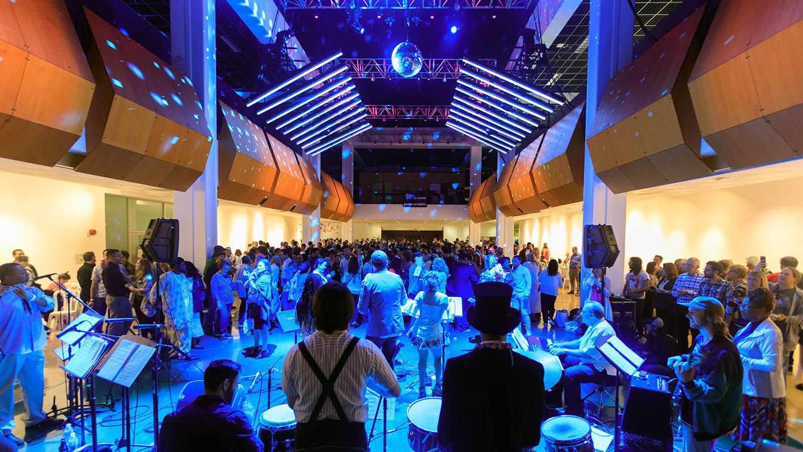 Packed Main Gallery lit up by blue lights and refractions from overhead disco ball