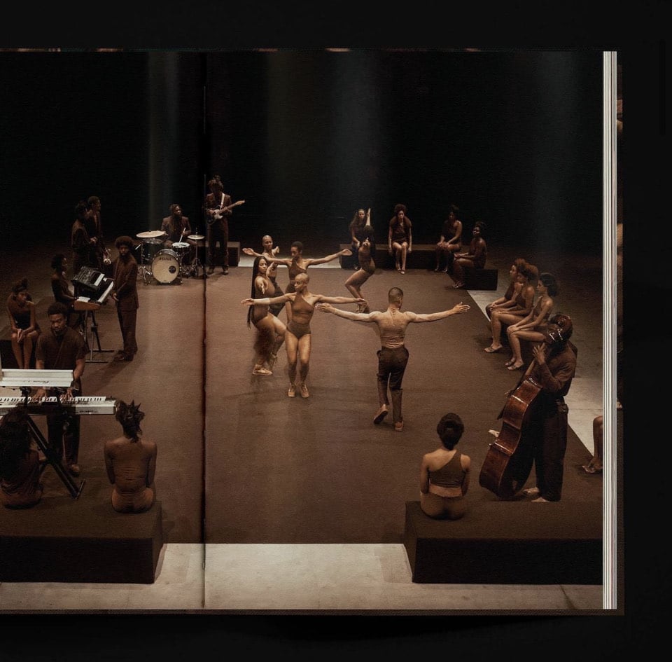 Overhead view of performing dancers surrounded by seated audience and instrumentalists