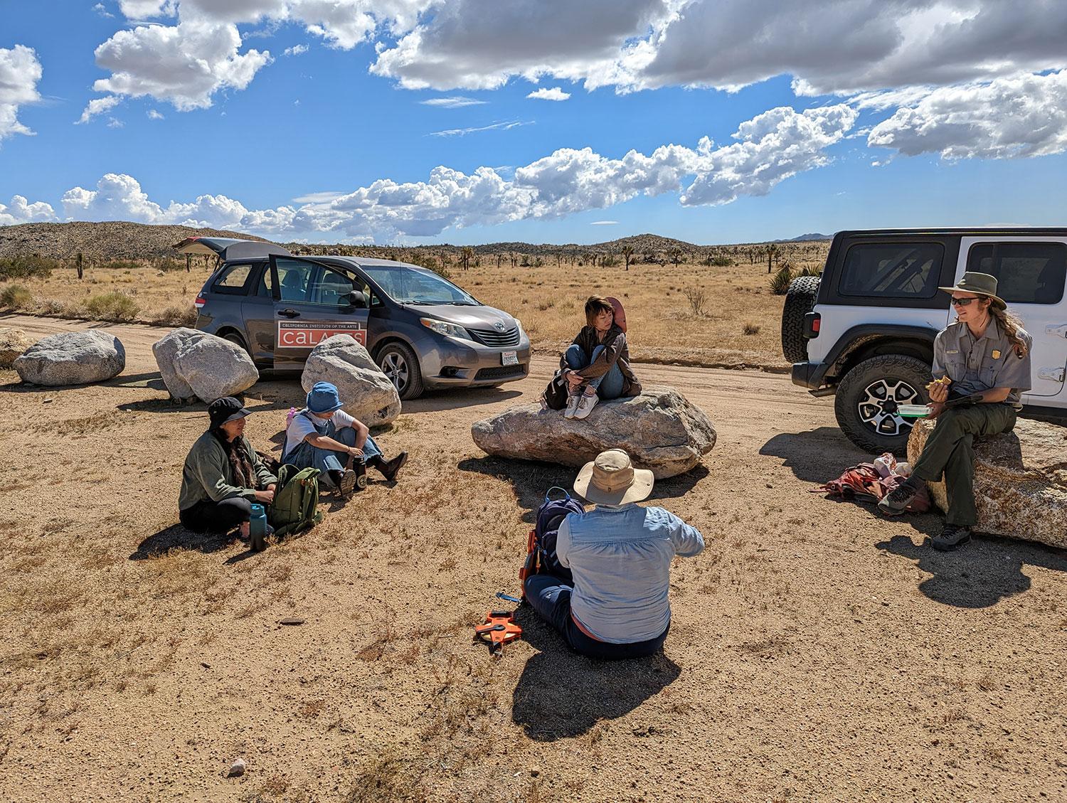 National Park Service ranger addresses people seated on desert ground or rocks